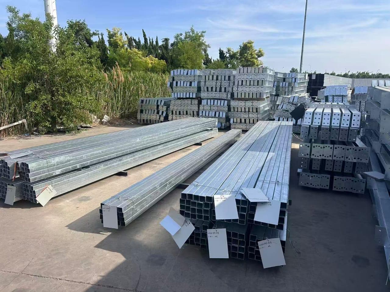 Galvanized square hollow steel tubes and palletized brackets in a storage yard