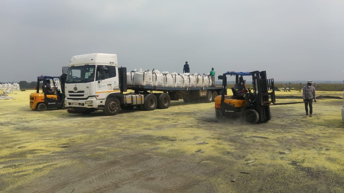 Forklifts loading bagged sulphur onto a truck for shipment